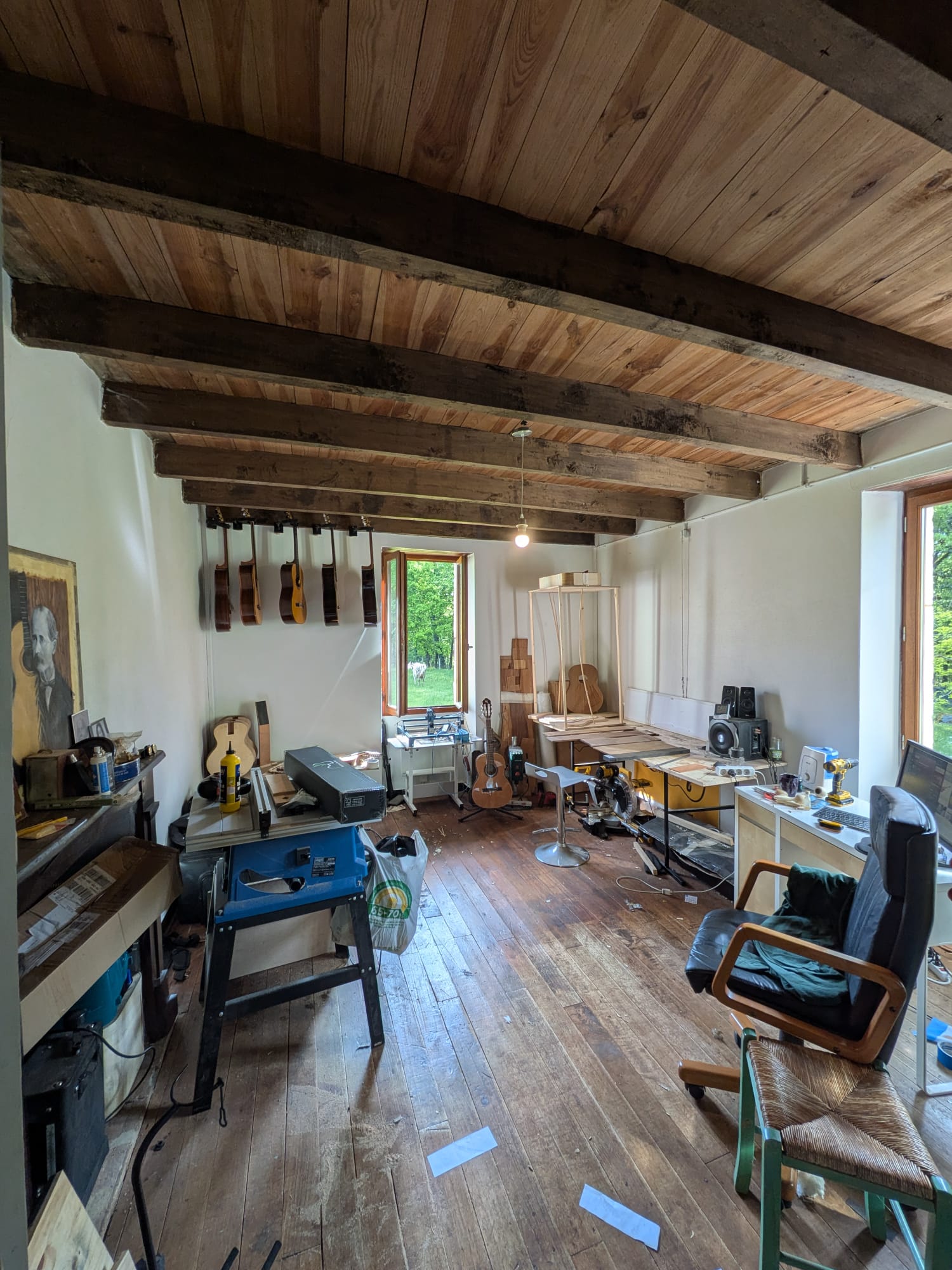 Interior del atelier de luthería NRG con guitarras artesanales colgadas y vigas de roble
